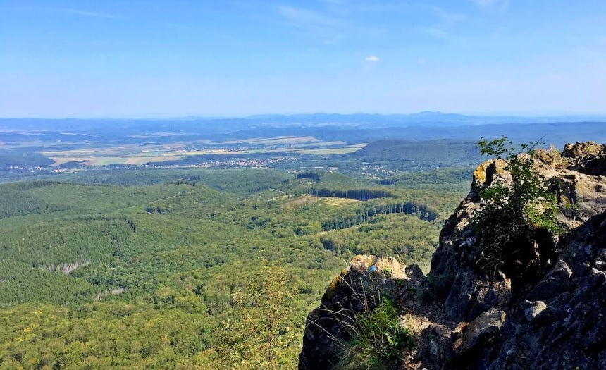 Egy magas hegy ormáról készült kép, ahol a fák tetejét is kicsiben lehet csak látni